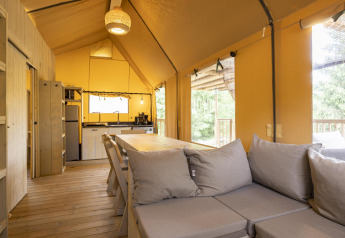 Interieur van Ranger Lodge safaritent op Baalse Hei in België met houten vloer, keuken en comfortabele bank.
