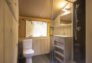 Baño dentro de la Ranger Lodge, una tienda safari en Baalse Hei, Bélgica, con ducha y lavabo modernos.