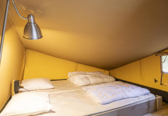 Interieur van een safaritent bij Ranger Lodge, Baalse Hei, België, met tweepersoonsbed en leeslamp.