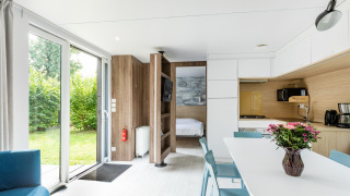 Lichte, moderne Taos XL-lodge bij Petite Suisse in België met open keuken, eettafel en tuinzicht.