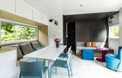Moderna cabaña Taos XL en Petite Suisse, Bélgica, con comedor, sofá y ventanas grandes con vista natural.