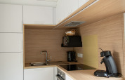 Modern kitchenette in Taos XL lodge at Petite Suisse, Belgium, with white cabinets and wood accents.