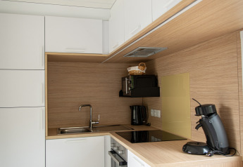 Modern kitchenette in Taos XL lodge at Petite Suisse, Belgium, with white cabinets and wood accents.