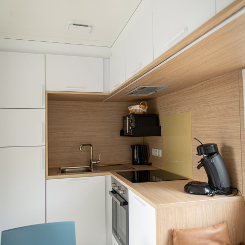 Moderne køkkenindretning i Taos XL lodge hos Petite Suisse, Belgien, med hvide skabe og træfinish.