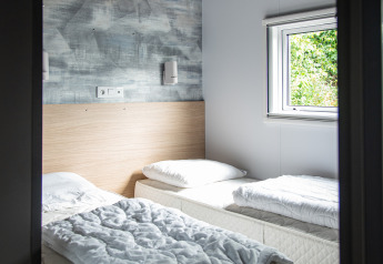 Lichte kamer met twee eenpersoonsbedden, wit beddengoed, Taos XL lodge in Petite Suisse, België.