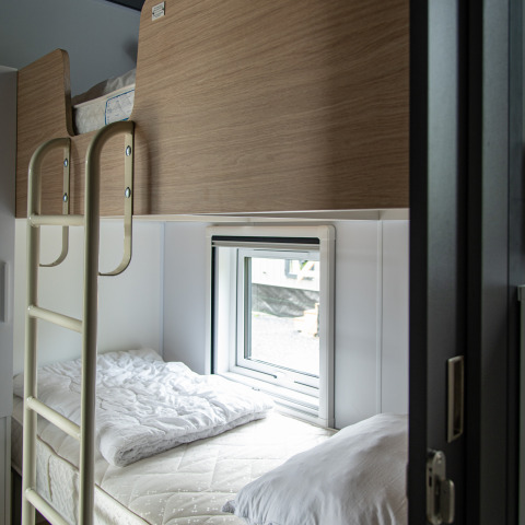 Modern stapelbed met houten panelen en raam in een Taos XL lodge bij Petite Suisse, België.