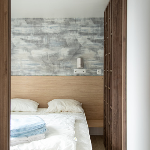 Dormitorio moderno en la cabaña Taos XL en Petite Suisse, Bélgica, con cama doble y pared decorativa.