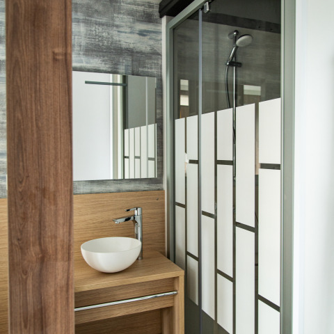 Moderne badeværelse med vask, spejl og brusekabine på Taos XL-lodgen, Petite Suisse, Belgien.