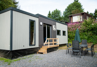 Moderna cabaña Taos XL en Petite Suisse, Bélgica, con zona de comedor exterior y entorno natural verde.