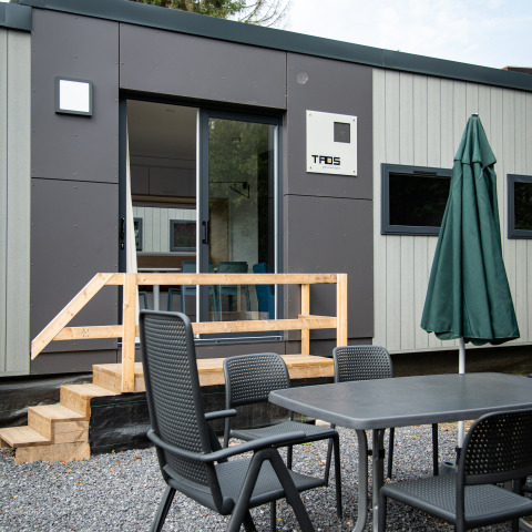 Zona de comedor exterior frente a una cabaña Taos XL moderna en Petite Suisse, Bélgica.
