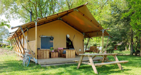Glamping Sunshine en Petite Suisse, Bélgica, con terraza de madera, bancos y rodeado de naturaleza.