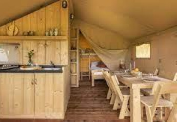 Interior photo of lodge Sunshine at Petite Suisse, Belgium, featuring wood furniture, kitchen and dining area.