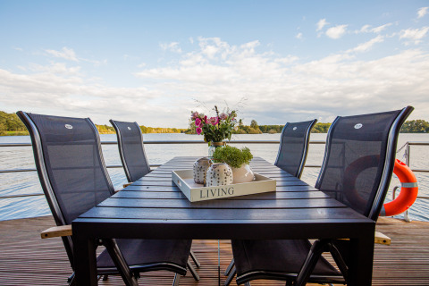 Mesa de comedor exterior con seis sillas en una casa flotante en Vakantiepark Leukermeer, Países Bajos.