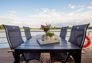 Mesa de comedor exterior con seis sillas en una casa flotante en Vakantiepark Leukermeer, Países Bajos.