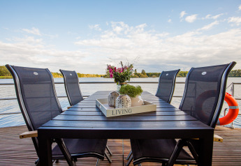 Mesa de comedor exterior con seis sillas en una casa flotante en Vakantiepark Leukermeer, Países Bajos.
