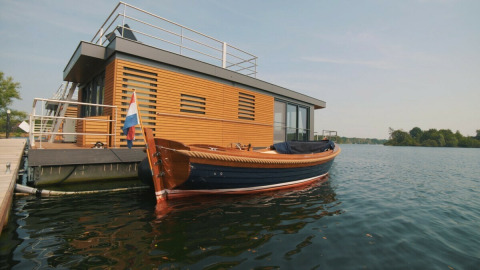 Modernes Hausboot am Wasser mit Holzverkleidung und Boot am Vakantiepark Leukermeer in den Niederlanden.