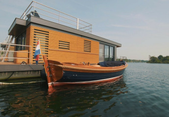 Casa flotante moderna de madera con barco amarrado en Vakantiepark Leukermeer, Países Bajos.
