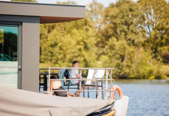 Dos personas se relajan y pescan en la terraza de una casa flotante en Vakantiepark Leukermeer, Países Bajos.