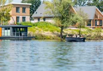 Photo d'une maison flottante et de maisons modernes au bord du lac à Vakantiepark Leukermeer, Pays-Bas.