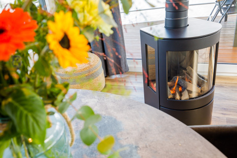 Chimenea moderna y flores coloridas en la sala del Floating House en Vakantiepark Leukermeer, Países Bajos.