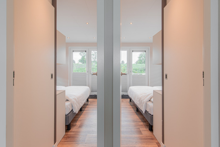 Binnenaanzicht van twee identieke slaapkamers op een woonboot bij Floating House, Vakantiepark Leukermeer, Nederland.