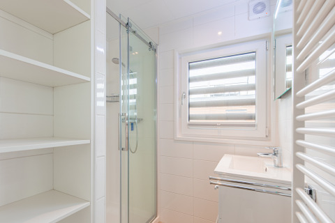 Lichte, moderne badkamer op een drijvend huis bij Vakantiepark Leukermeer, Nederland, met douche en raam.
