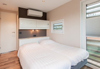 Dormitorio moderno con dos camas individuales en una casa flotante en Vakantiepark Leukermeer, Países Bajos.