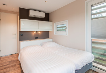 Dormitorio moderno con dos camas individuales en una casa flotante en Vakantiepark Leukermeer, Países Bajos.