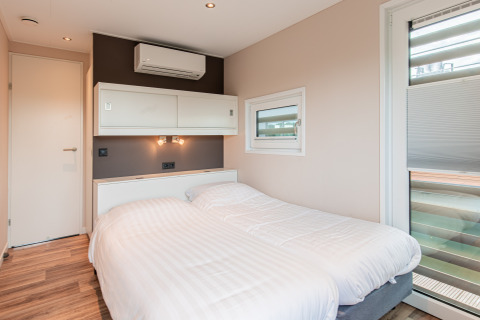 Dormitorio moderno con dos camas individuales en una casa flotante en Vakantiepark Leukermeer, Países Bajos.