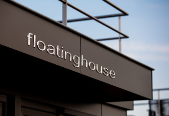 Letrero de 'floatinghouse' en una casa flotante en Vakantiepark Leukermeer, Países Bajos, cielo azul.