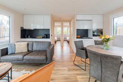Bright, modern houseboat interior at Vakantiepark Leukermeer, Netherlands, with kitchen, living and dining area.