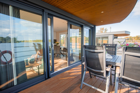 Moderne Hausboot mit Glastüren und Terrasse am Wasser im Floating House, Vakantiepark Leukermeer, Niederlande.
