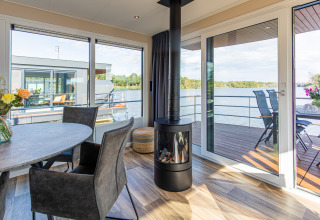 Uitzicht vanuit de woonkamer op een woonboot, Floating House, Vakantiepark Leukermeer, met terras aan het water.