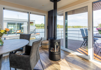 Vue du salon d'une péniche, Floating House, Vakantiepark Leukermeer, avec déco moderne et terrasse au bord du lac.