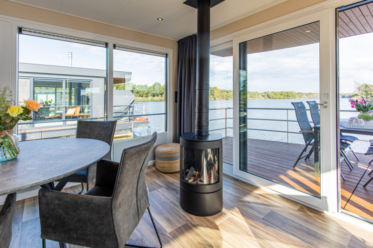 Uitzicht vanuit de woonkamer op een woonboot, Floating House, Vakantiepark Leukermeer, met terras aan het water.