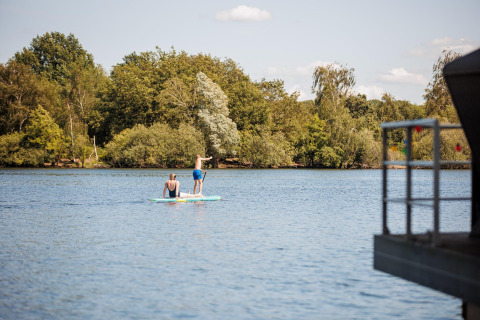 Due persone fanno paddleboard su un lago vicino alla Floating House del Vakantiepark Leukermeer, Paesi Bassi.