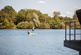 Due persone fanno paddleboard su un lago vicino alla Floating House del Vakantiepark Leukermeer, Paesi Bassi.