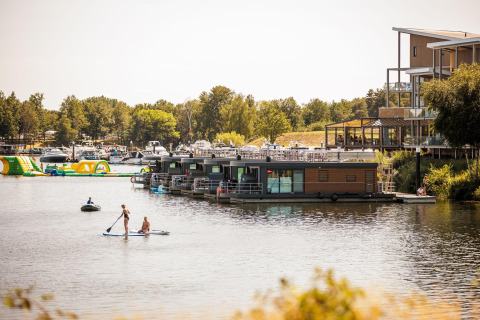Blick auf das Hausboot Floating House im Vakantiepark Leukermeer in den Niederlanden mit Paddlern.