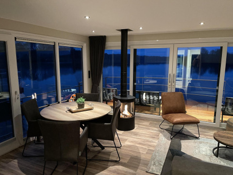 Salón moderno con chimenea en el houseboat Floating House en Vakantiepark Leukermeer, Países Bajos al anochecer.