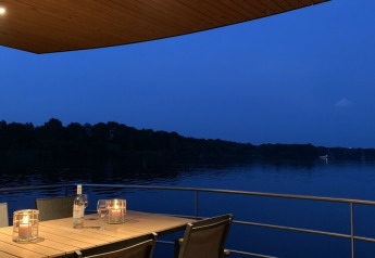 Foto nocturna en el Floating House con mesa iluminada por velas y vistas al lago en Leukermeer, Países Bajos.