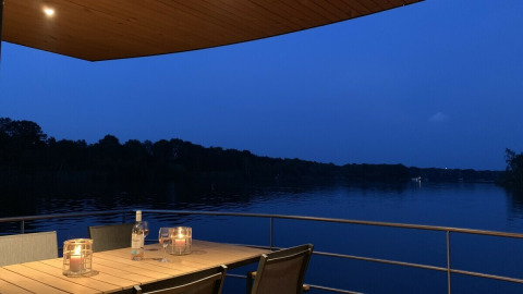 Foto nocturna en el Floating House con mesa iluminada por velas y vistas al lago en Leukermeer, Países Bajos.