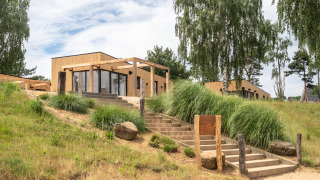 Exterior view of Beachlodge Deluxe at Vakantiepark Leukermeer, Netherlands, nestled in green nature and trees.