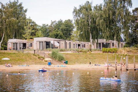 Beachlodge Deluxe en Vakantiepark Leukermeer, Países Bajos, con familias disfrutando del lago y la playa.
