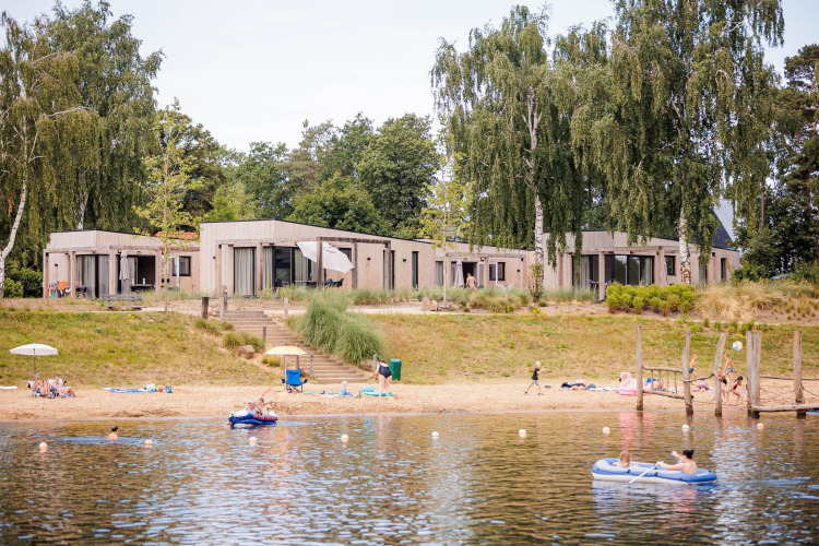 Beachlodge Deluxe im Vakantiepark Leukermeer, Niederlande, mit Gästen am Strand und am Wasser.