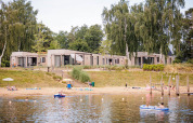 Beachlodge Deluxe im Vakantiepark Leukermeer, Niederlande, mit Gästen am Strand und am Wasser.