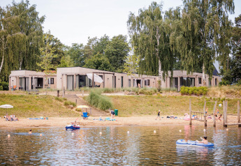 Beachlodge Deluxe at Vakantiepark Leukermeer in the Netherlands with guests relaxing by the lake and beach.