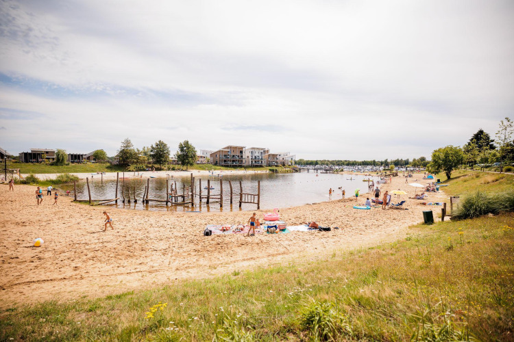 Foto eines Sandstrandes an einer Lodge mit Menschen, die am sonnigen Ufer entspannen und spielen.