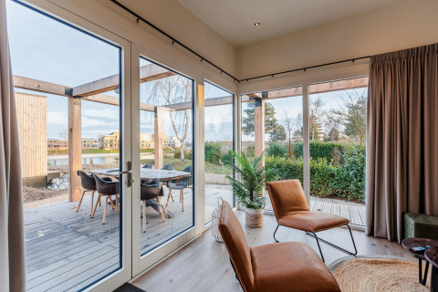 Helle und moderne Lodge mit großen Fenstern, Blick auf die Terrasse und Garten im Vakantiepark Leukermeer, Niederlande.