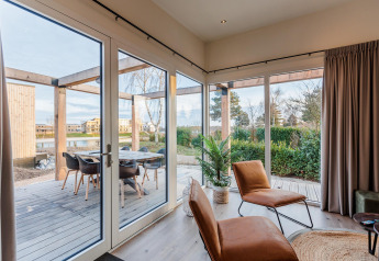 Bright, modern lodge with large windows, outdoor seating, and garden view at Vakantiepark Leukermeer in the Netherlands.