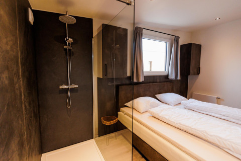 Habitación moderna con ducha, cama doble y ventana en Beachlodge Deluxe ǀ to, Vakantiepark Leukermeer, Países Bajos.
